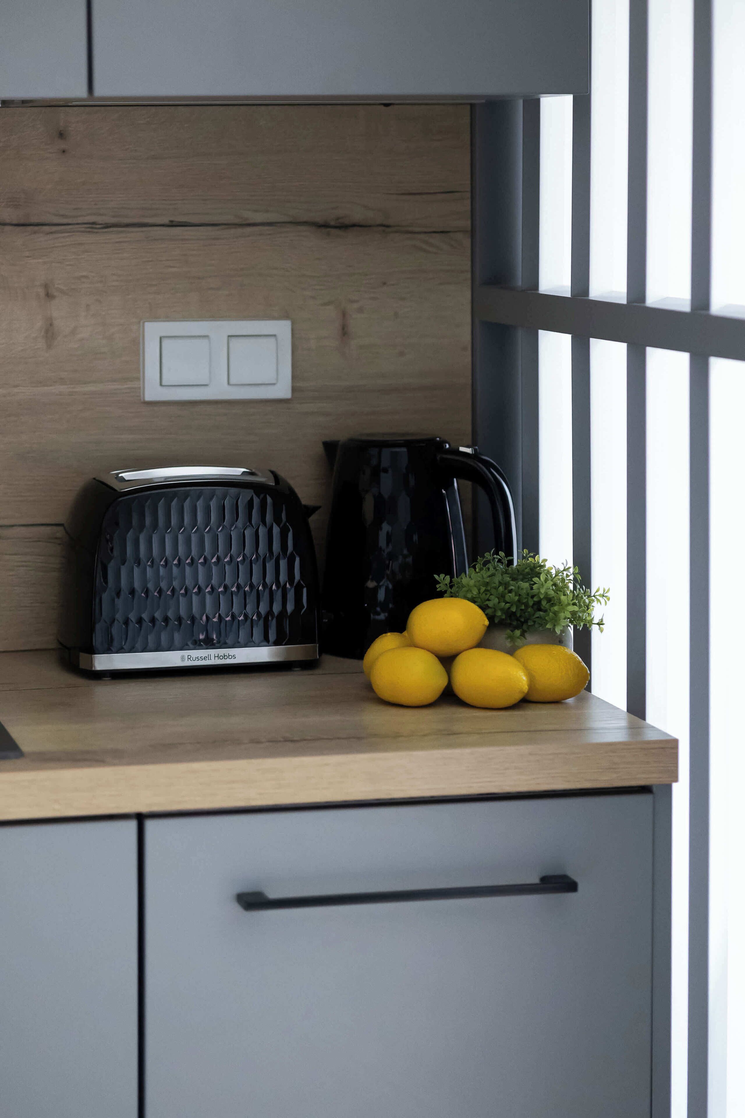 Una encimera de cocina con un tostador, una tetera y limones.