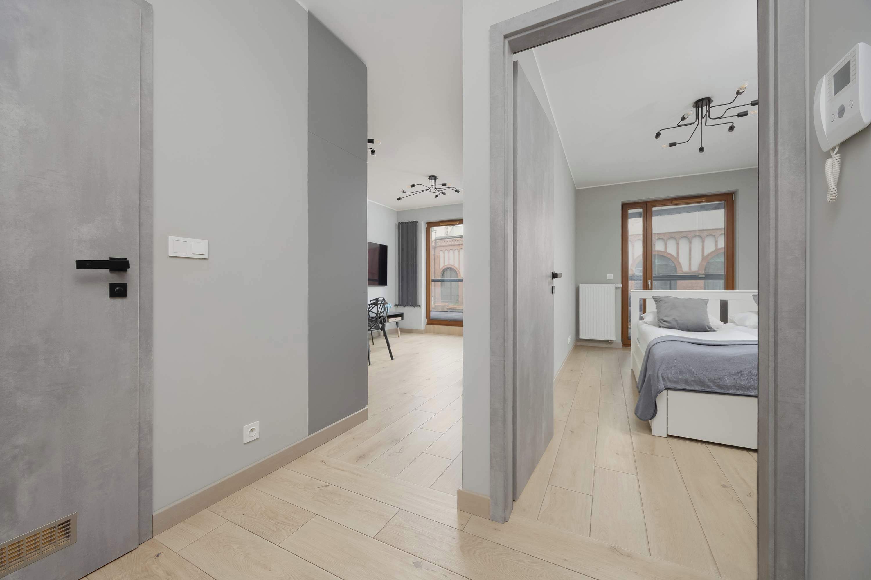 A modern bedroom with a bed, a bedside table, and a window with a view.