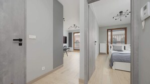A modern bedroom with a bed, a bedside table, and a window with a view. - Comfortable Apartment in the Center | Parking, AC, Balcony (Warszawa)
