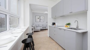 A modern kitchen with a large window, a dining area with a sofa, and a small table. - Modern Apartment | Air Conditioning | Close to Parks (Warszawa)