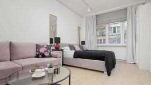 A modern living room with a sofa, a coffee table, and a bed. - Air-conditioned Studio in Warsaw | Close to Parks (Warszawa)