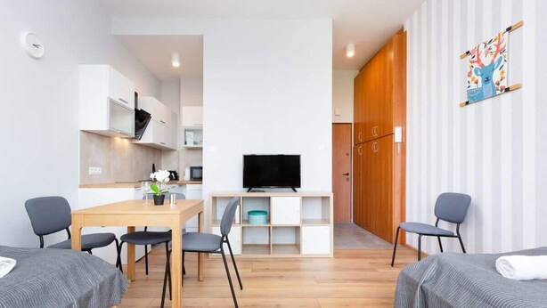 A modern room with a bed, a desk, a TV, and a dining area. - Cozy Studio in Mokotow | Close to Metro and Park (Warszawa)