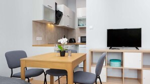 A compact living space with a dining area, kitchenette, and a TV. - Cozy Studio in Mokotow | Close to Metro and Park (Warszawa)