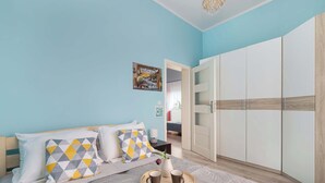 A bedroom with a bed, a bedside table, a wardrobe, and a tray with two cups.