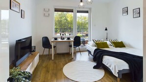 A modern bedroom with a bed, a desk, and a TV. - Stylish Studio with Balcony | Modern Building (Warszawa)