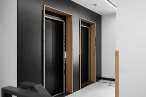 A hallway with two closed doors, a white floor, and a light fixture on the ceiling.