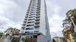 A tall residential building with multiple balconies and a sign indicating 2 bedrooms available for sale. - Spacious,New Apartment with WiFi,Gym and heated pool in Lavington, Nairobi (Nairobi)