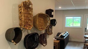 A modern living room with a large wall-mounted basket collection, a sofa, and a dining area. - Spacious 2BR Retreat in Nature (Burk's Falls)