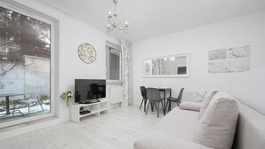 Ett modernt vardagsrum med en soffa, TV, matbord, stolar och ett stort fönster.