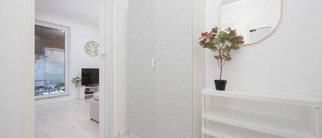 Un baño moderno con cabina de ducha blanca, un espejo grande y una planta en maceta.