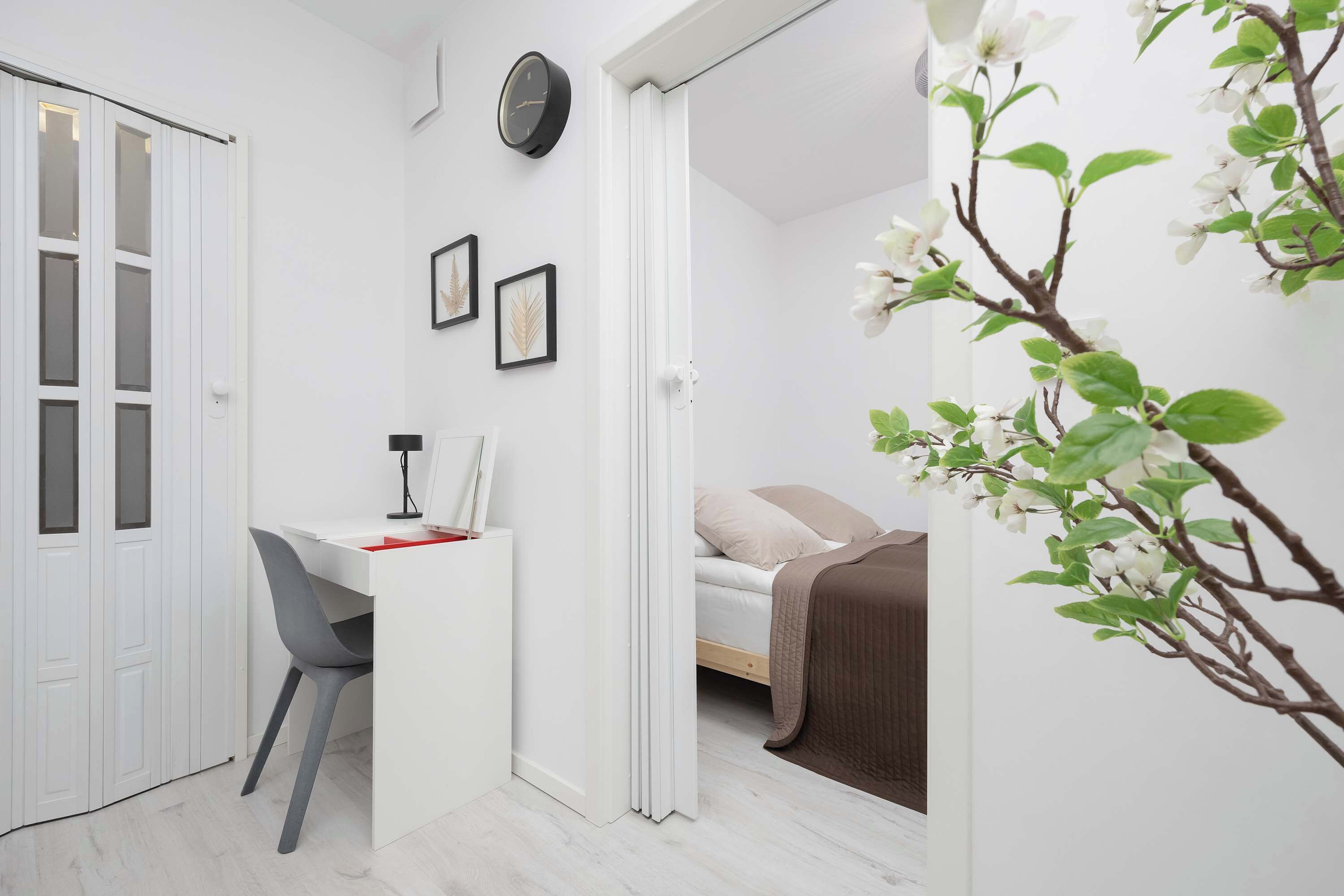 Une petite pièce comprenant un lit, un bureau avec une chaise et une armoire blanche.