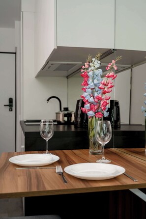 A dining table with two white plates, a fork, and a wine glass, set against a modern kitchen backdrop.
