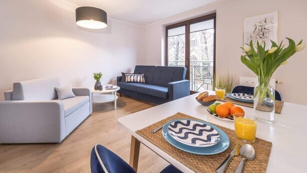 A modern living room with a sofa, coffee table, and dining area. - Cozy Studio in Downtown Sopot | Close to the Beach and the Pier (Sopot)