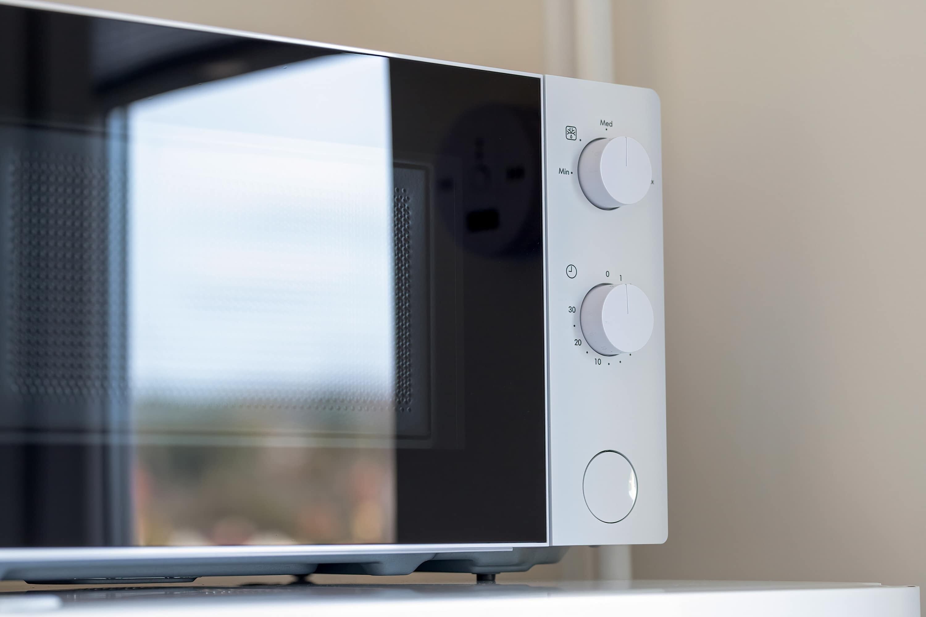 A microwave with control knobs and a power outlet.
