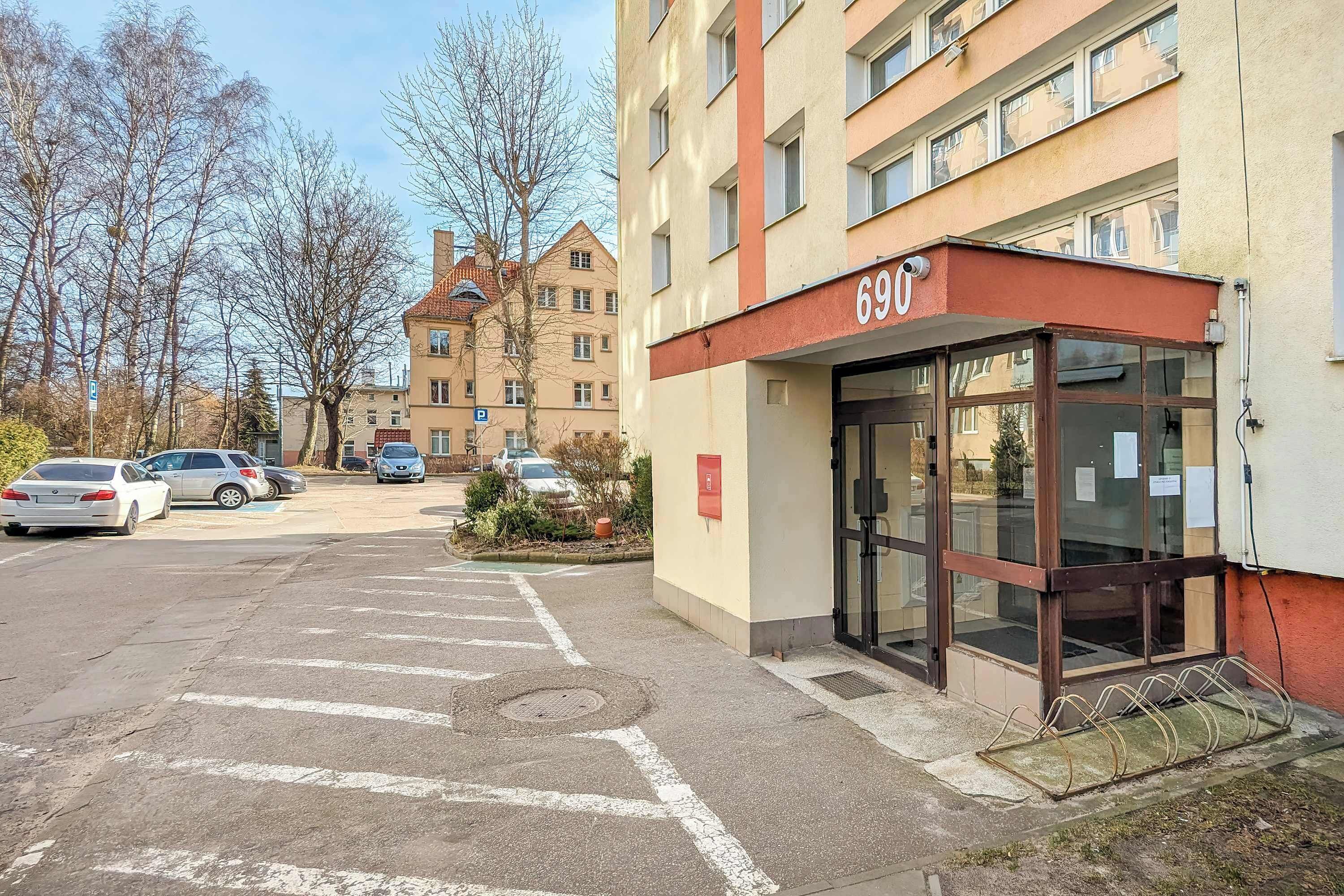 Un bâtiment portant le numéro « 690 » et un parking avec des voitures.