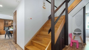 A staircase with wooden steps and black railings, leading to a room with a white wall and a geometric wall art piece.