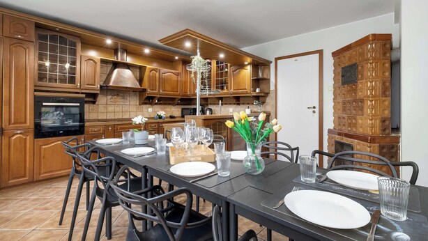 A modern kitchen with wooden cabinets, a dining table set for four, and a decorative vase with flowers.