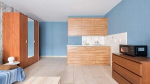 Eine kleine Küche mit Holzschränken, einer Mikrowelle und einem Spülbecken.