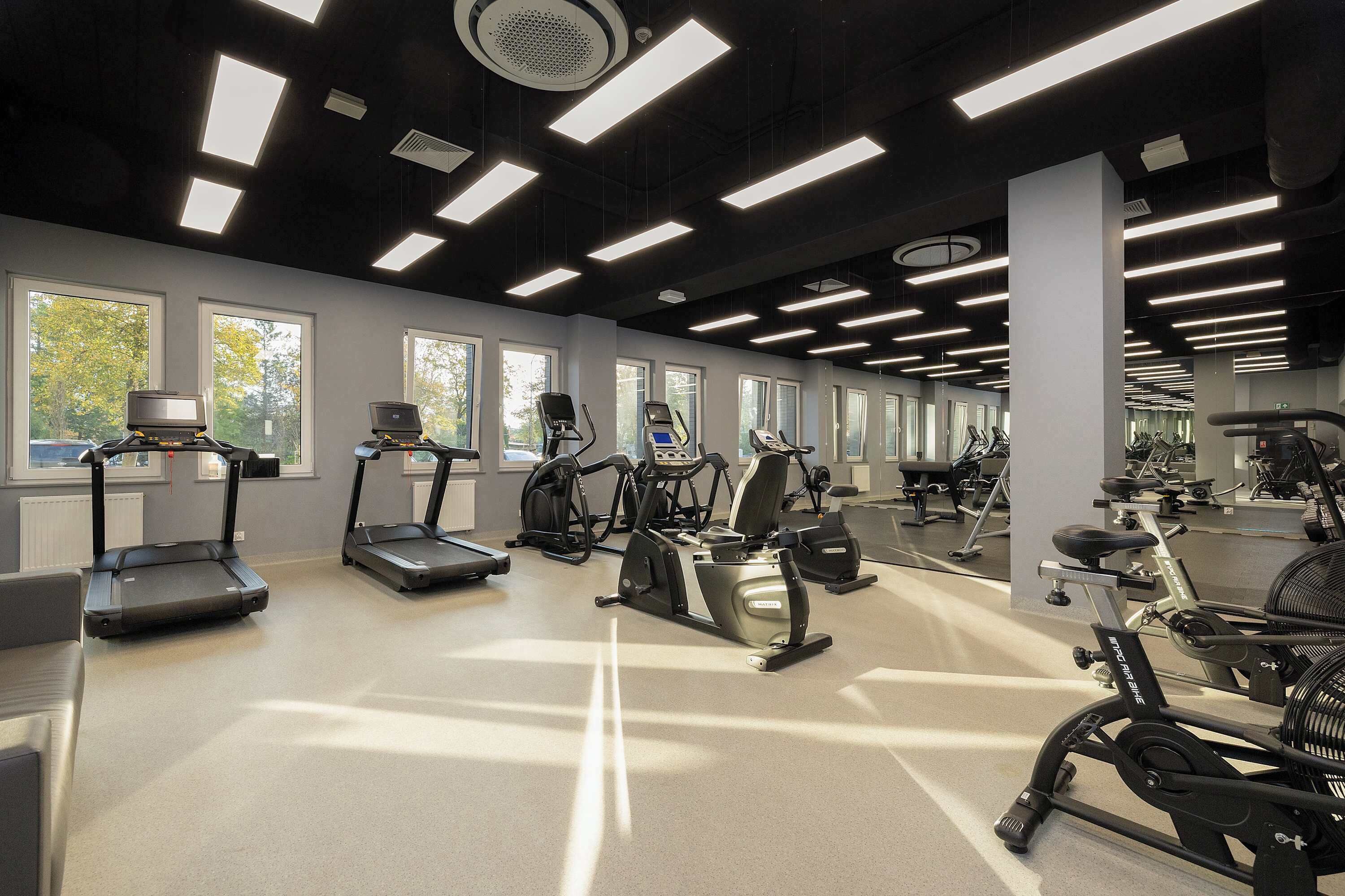 Une salle de sport équipée de tapis de course, d’appareils elliptiques et de vélos d’appartement.