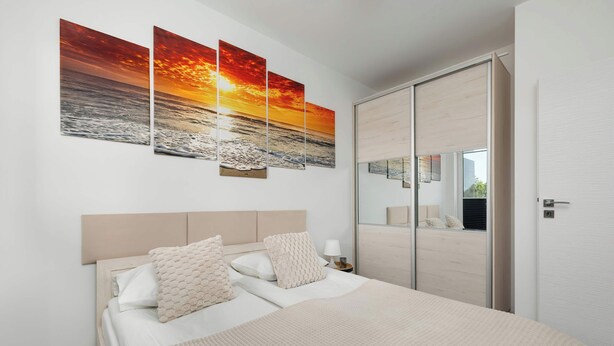A modern bedroom with a large bed, a headboard, and a nightstand with a lamp.