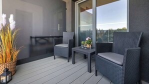 A balcony with wicker furniture, a small table, and a potted plant.