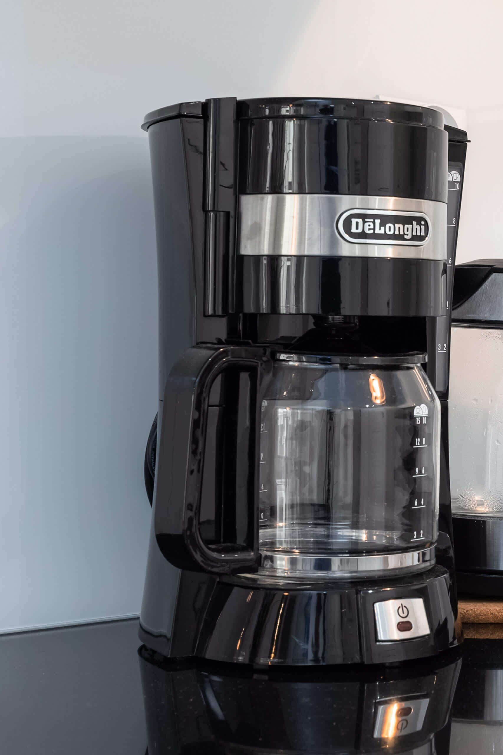 Eine schwarze DeLonghi Kaffeemaschine mit transparentem Wasserbehälter und digitaler Anzeige.