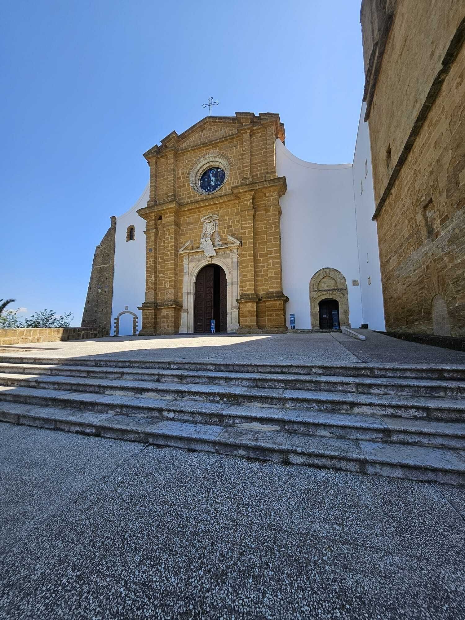 Eine Kirche mit auffälligem Eingang, einer Turuhr und einer Treppe, die zu ihr hinaufführt.