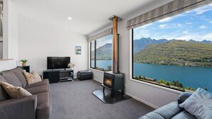 A modern living room with a large window, a fireplace, a sofa, and a television. - Perfect Place To Stay! Views! (Queenstown)