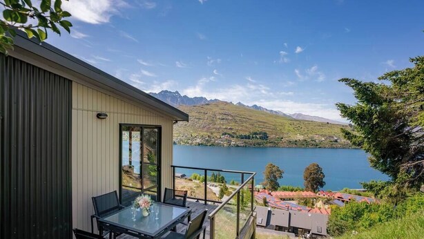 A modern building with a glass balcony overlooking a lake and mountains. - Perfect Place To Stay! Views! (Queenstown)