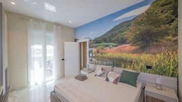 A bedroom with a bed, a nightstand, a lamp, a door, and a view of a landscape mural.