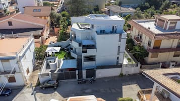 A multi-story residential building with a flat roof, solar panels, and a gated entrance.