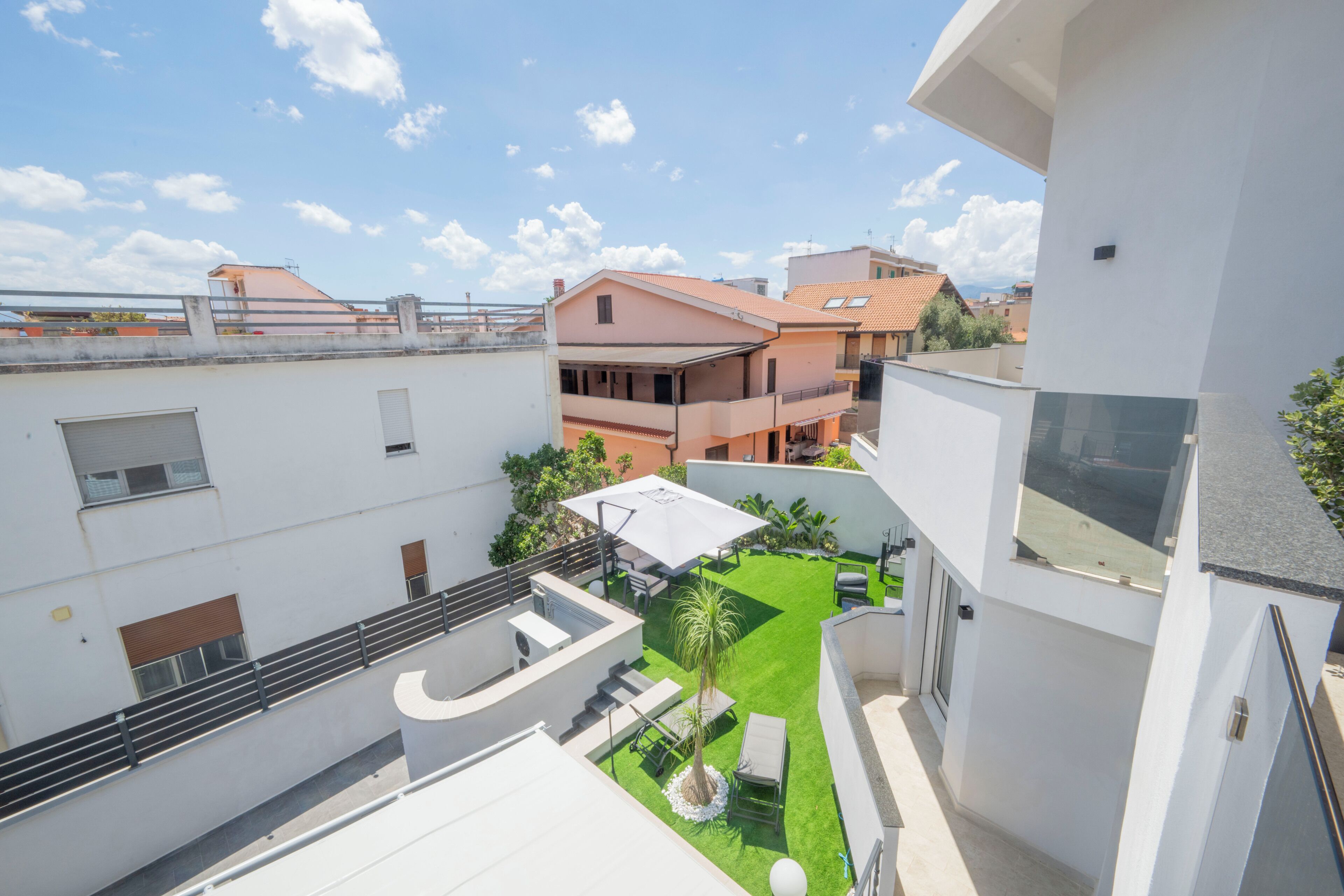 Un immeuble résidentiel doté d’une terrasse sur le toit, d’un petit jardin et offrant une vue sur les maisons voisines.