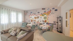 A living room with a map wall, a sofa, a dining table, and a coffee table. - Exclusive B&B Villa Rosa (Messina)
