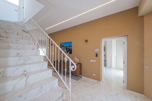 A staircase with white railings leading to a landing with a brown wall and a door. - Exclusive B&B Villa Rosa (Messina)