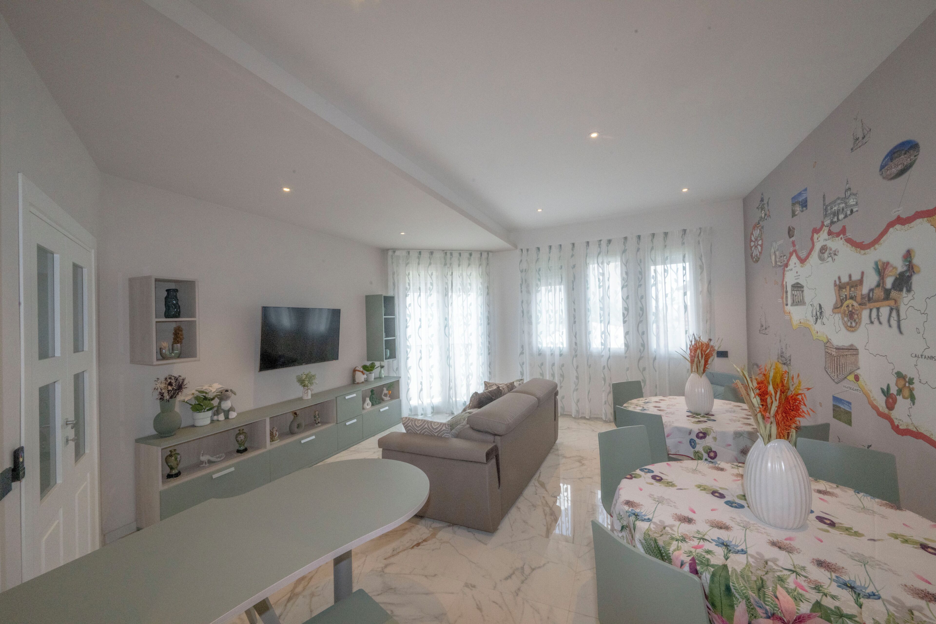 Ein modernes Wohnzimmer mit einer Couch, einem Esstisch und einem an der Wand befestigten Fernseher.