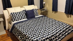 Un dormitorio con cama, mesita de noche, lámpara y un reloj de pared.