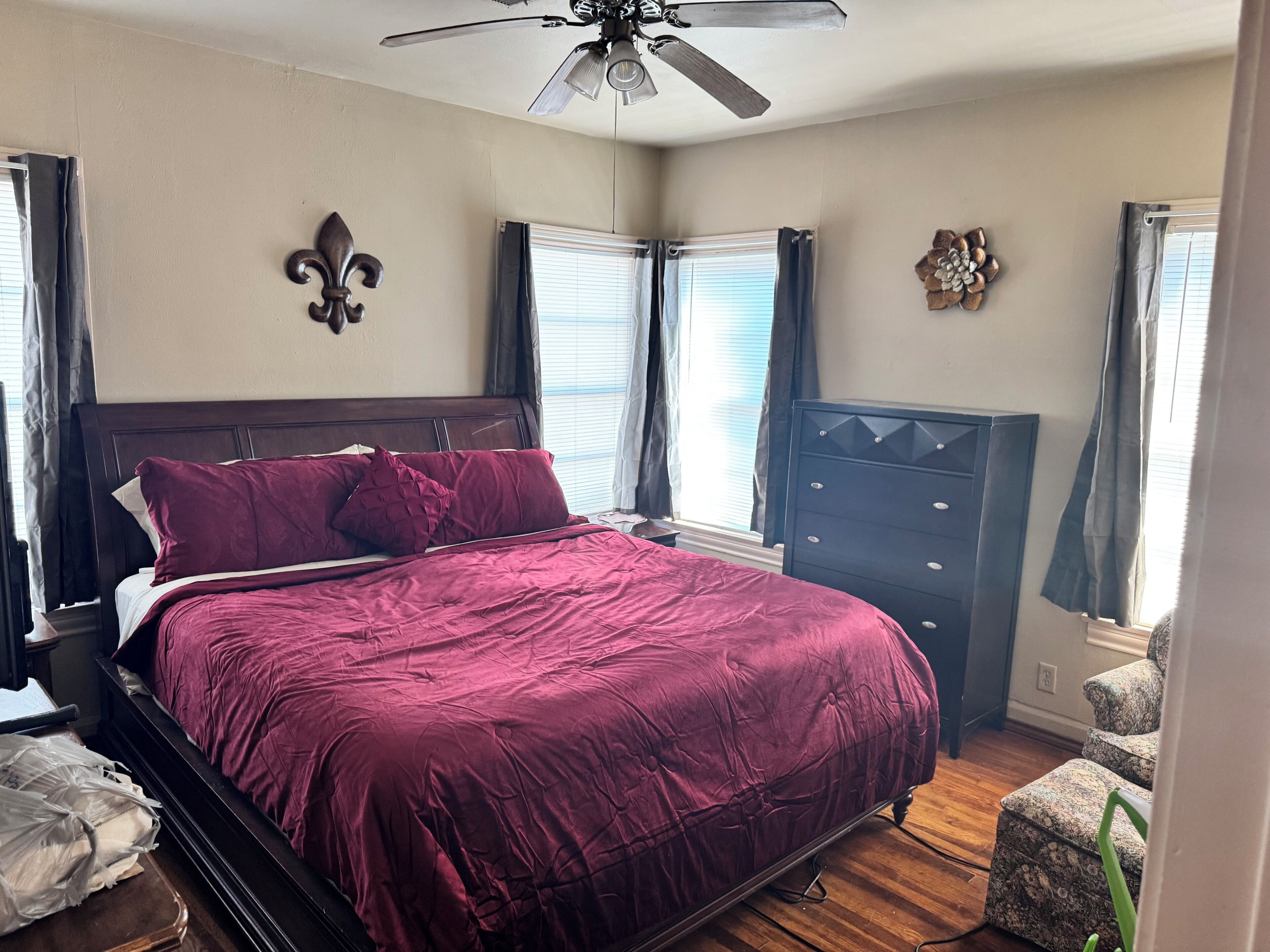 A bedroom with a large bed, a dresser, and a ceiling fan.