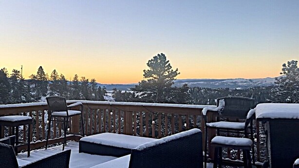 A snow-covered deck with outdoor seating and a view of a snowy landscape.