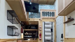 Une cuisine compacte avec des meubles en bois, un réfrigérateur noir et un petit coin repas comprenant une table et des chaises.