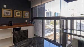 Ein modernes Interieur mit Küchenzeile, einem Korbstuhl und einem großen Fenster mit Blick auf die Stadt.