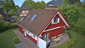 A red house with a sloped roof, a small porch with a bench, and a number '9' on the side. - Vacation home Seerose am Elbdeich in Otterndorf (Otterndorf)
