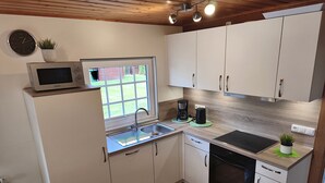 A compact kitchen with white cabinets, a microwave, a coffee maker, and a dishwasher. - Vacation home Seerose am Elbdeich in Otterndorf (Otterndorf)