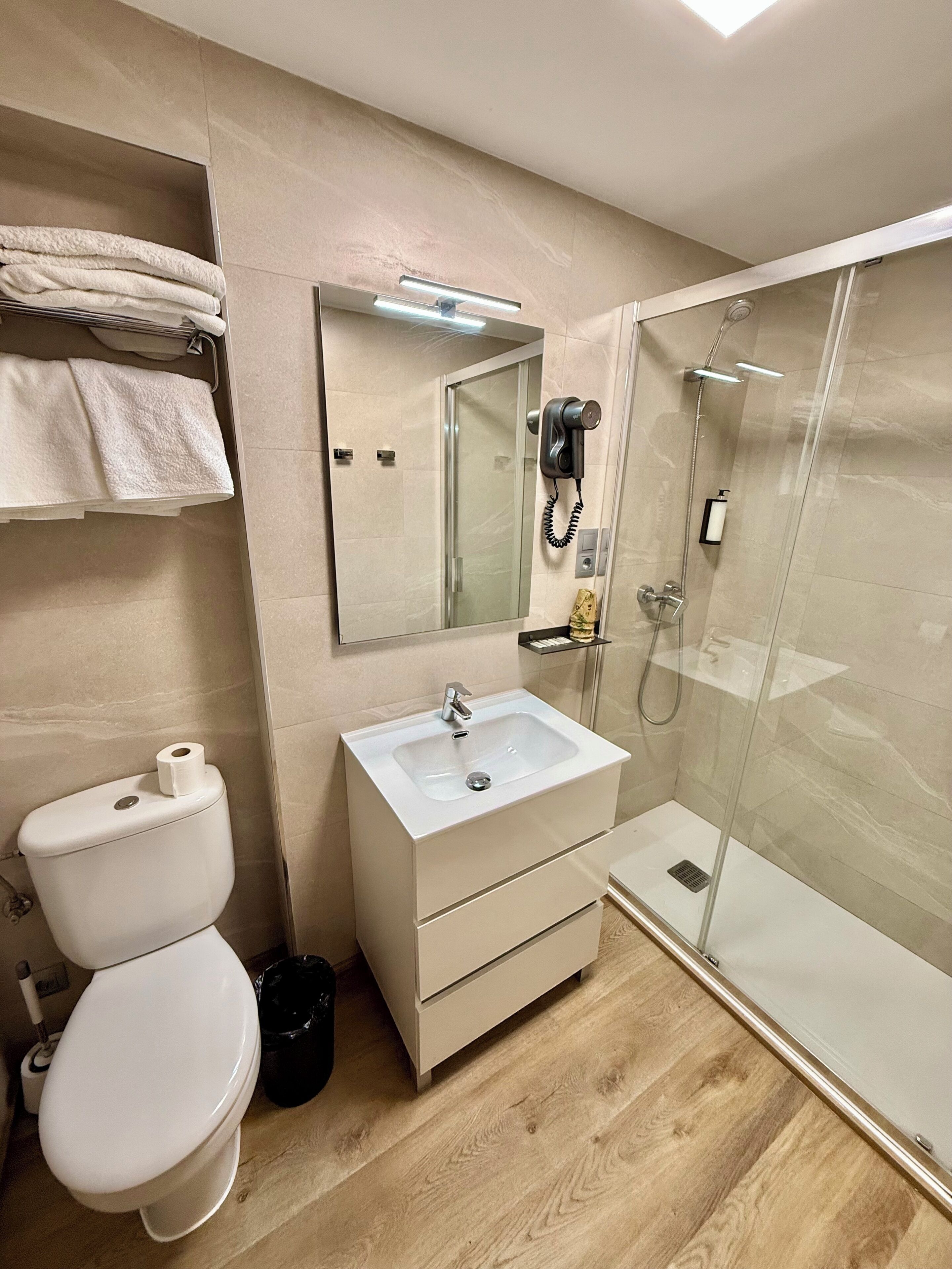 A bathroom with a toilet, sink, and glass shower enclosure.