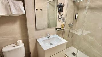 A bathroom with a toilet, sink, and glass shower enclosure.