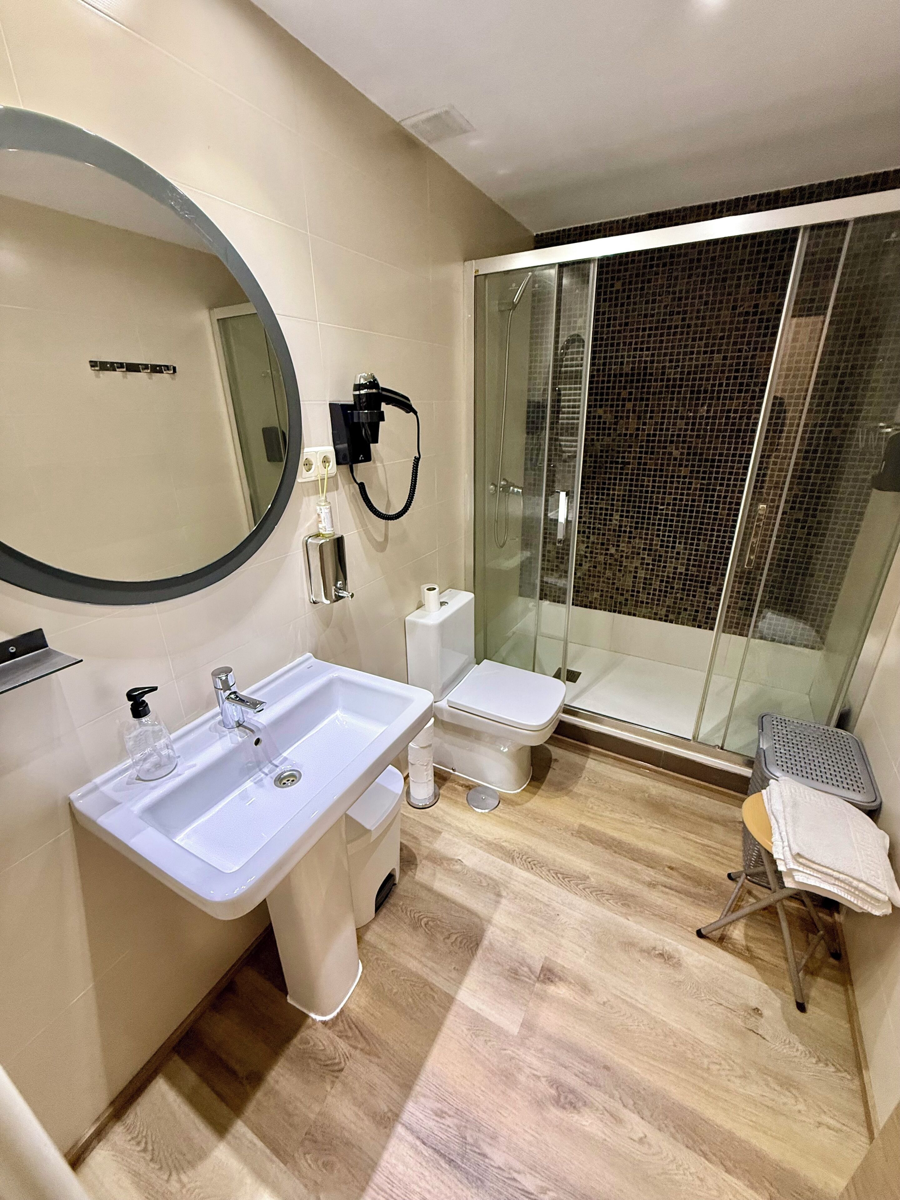 Een moderne badkamer met een grote spiegel, een wastafel, een toilet en een douchecabine met glazen wanden.