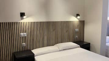 Un dormitorio moderno con una cama grande, dos mesitas de noche, una lámpara de pared y un cabecero de listones de madera.