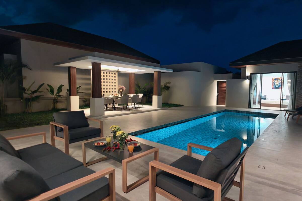 A modern outdoor pool area with seating and a covered patio.