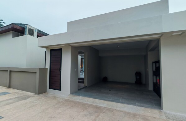 A modern building with a flat roof, a concrete entrance, and a visible door.