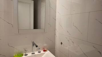 A bathroom with a white sink, a mirror, and a light fixture above the mirror.