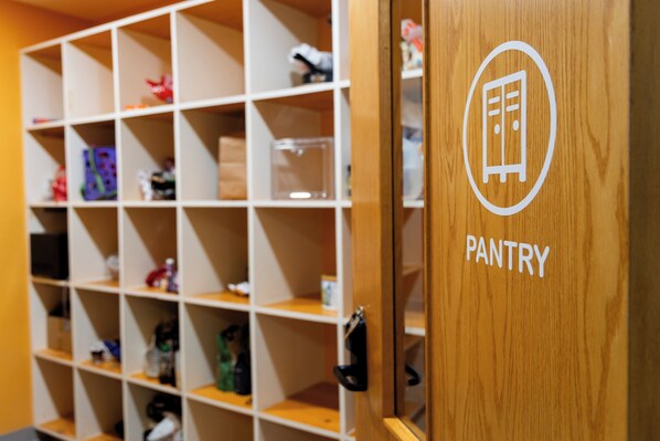 A wooden pantry with labeled shelves and a door marked 'PANTRY.'